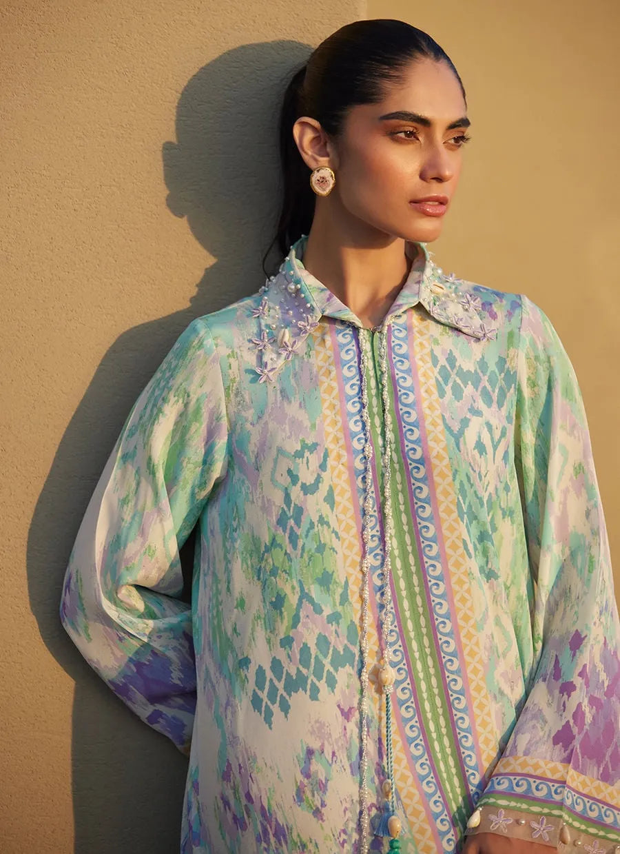 Woman wearing a colorful patterned shirt against a beige background