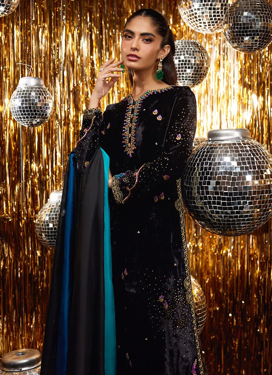 Woman in a black and gold traditional outfit with disco balls and gold curtain background