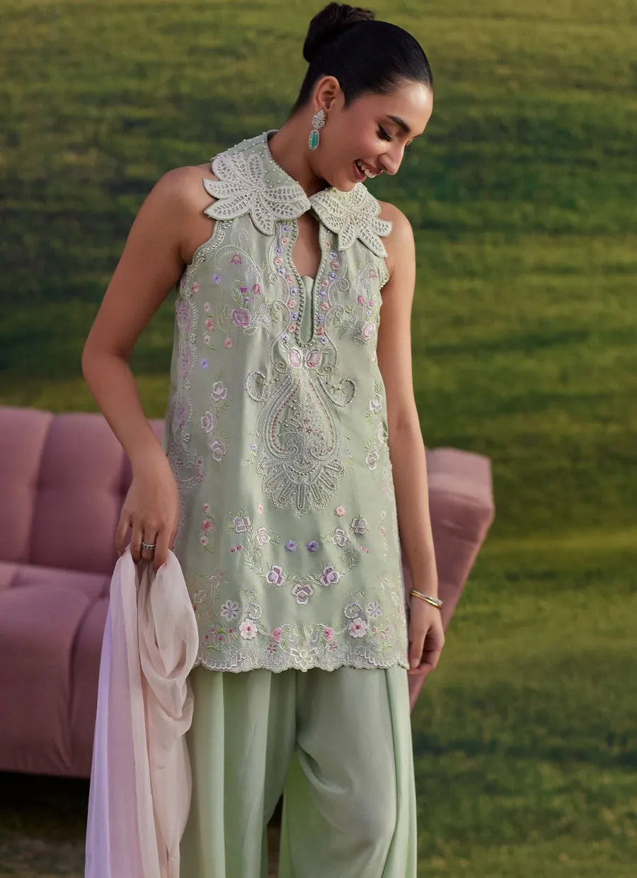 Woman wearing a light green embroidered top and pants in an outdoor setting.