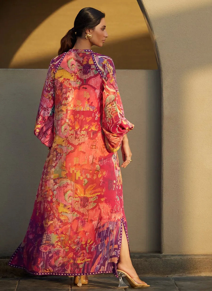 Woman wearing a colorful patterned dress standing against a neutral wall.