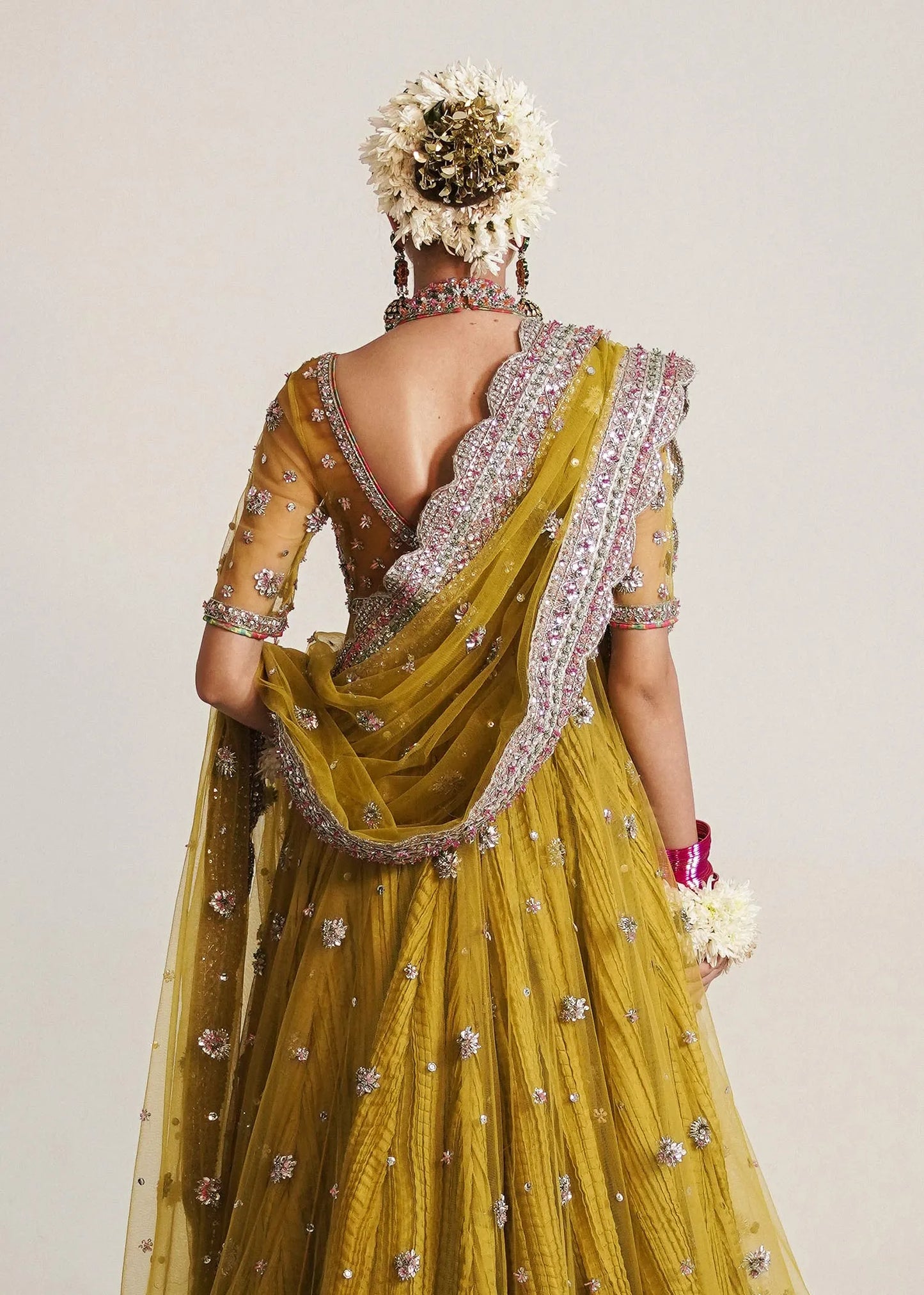 Yellow saree with intricate details and a floral headpiece on a plain background