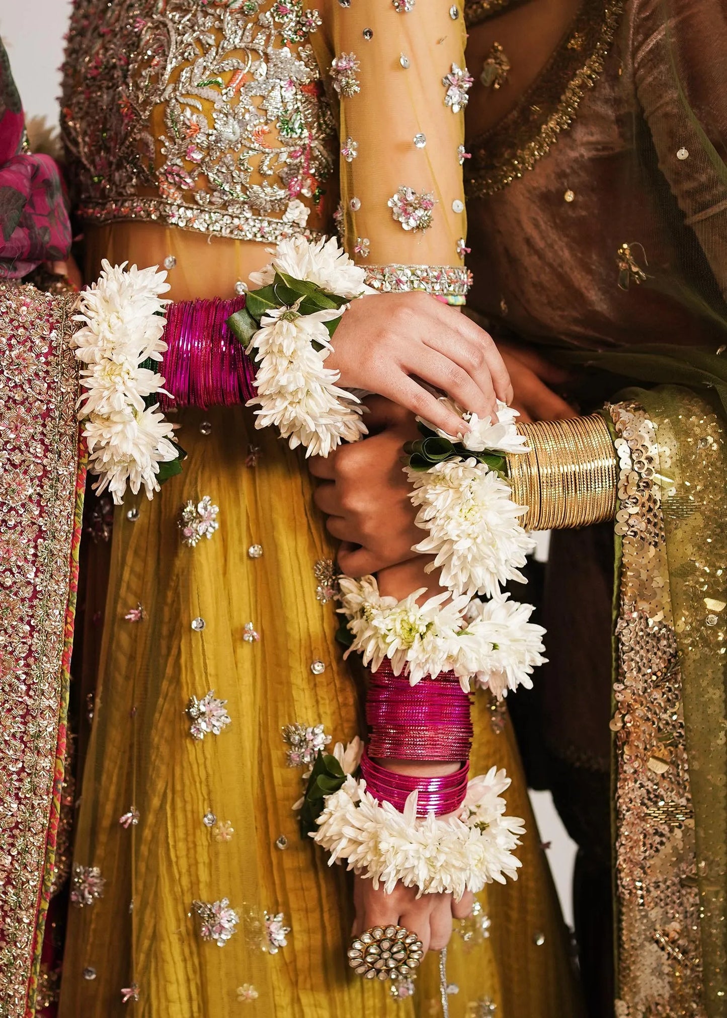 Close-up of hands holding white flowers with traditional attire in the background