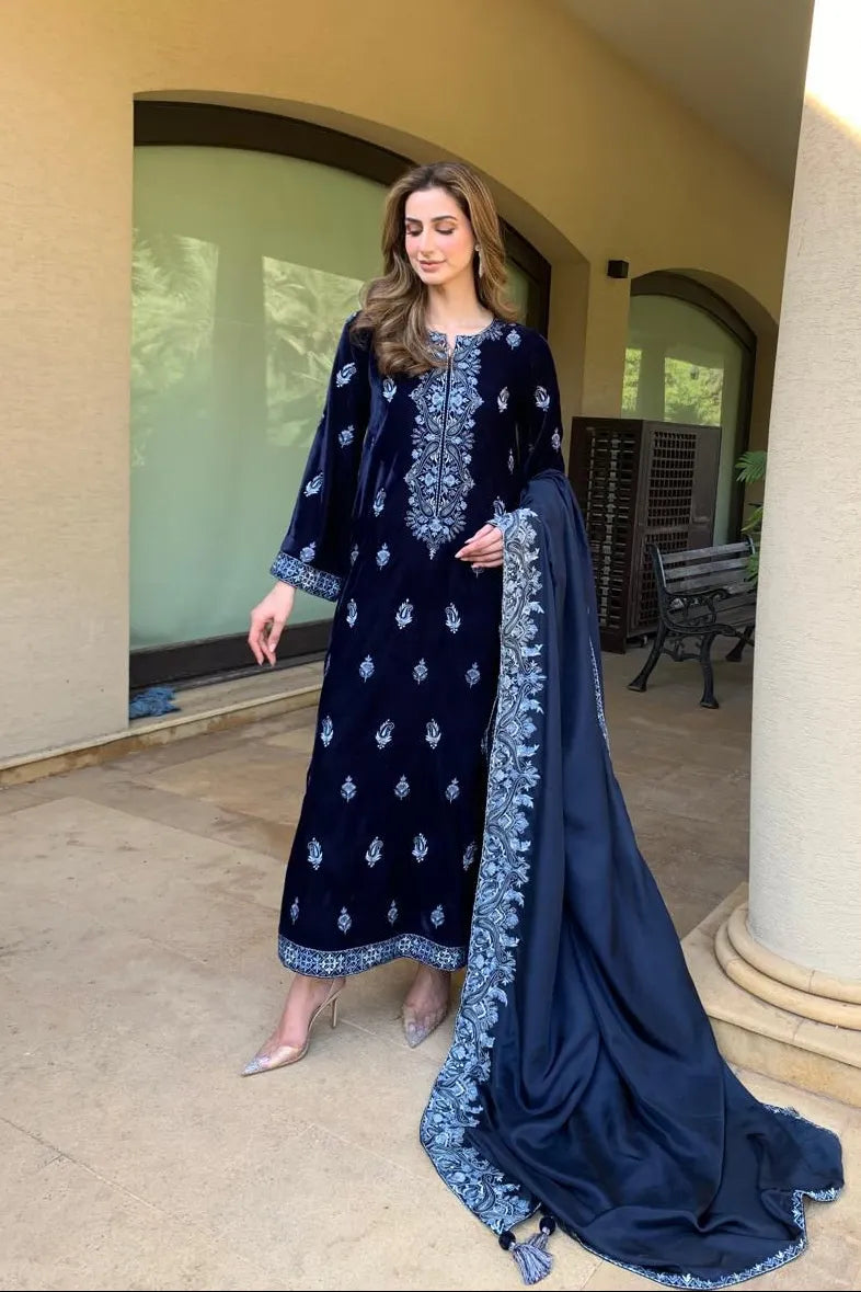 Woman in a navy blue embroidered outfit with a matching dupatta standing outdoors.