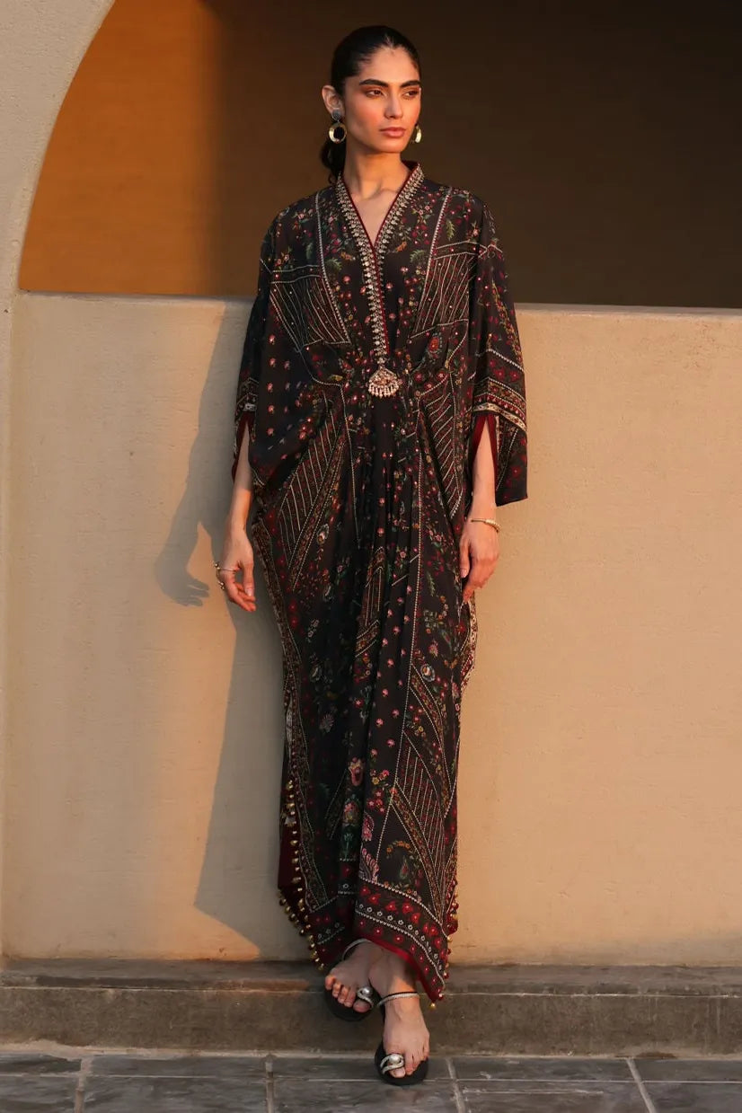 Woman wearing a patterned dress standing against a beige wall.