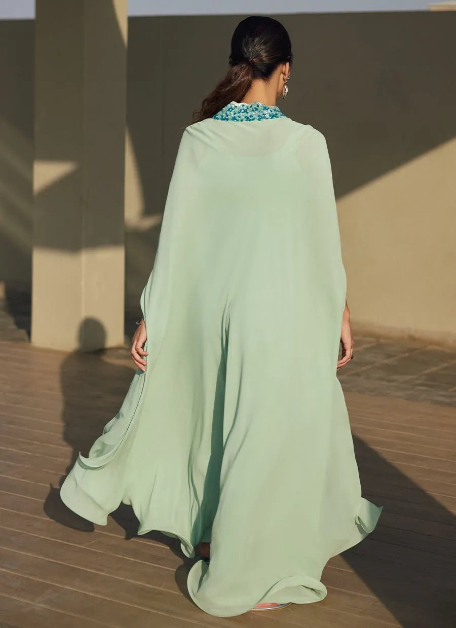 Woman wearing a light green dress with a patterned collar in an indoor setting