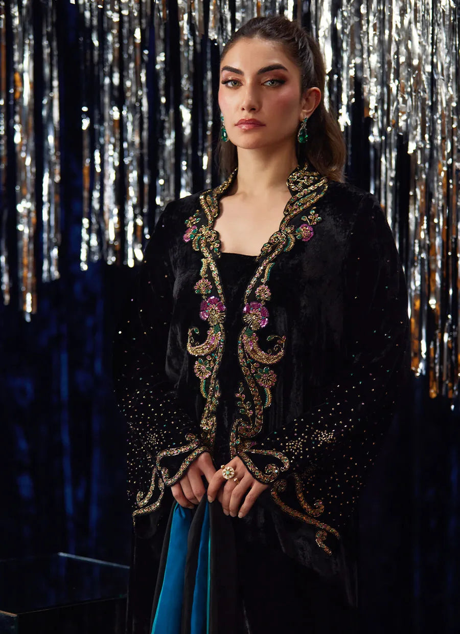 Woman wearing a black embroidered jacket with a sequined curtain background