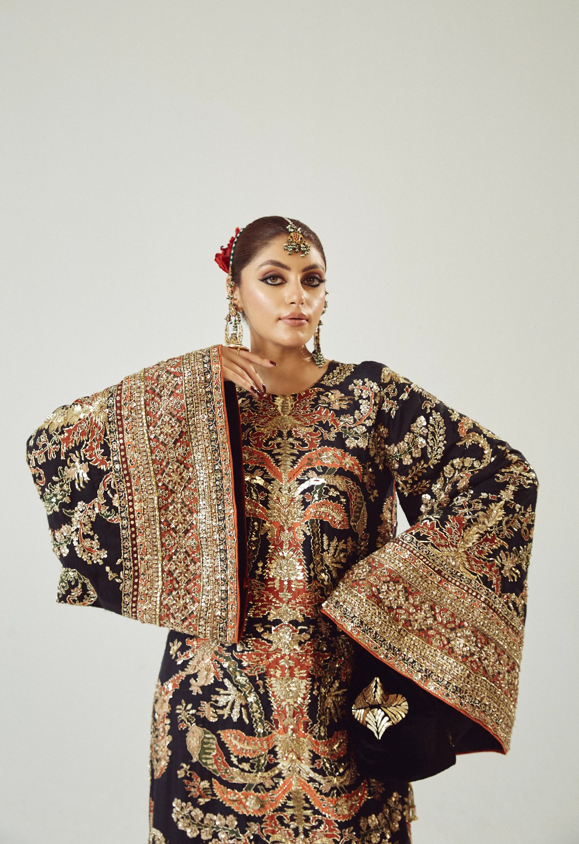 Woman wearing a traditional embroidered outfit with a plain background