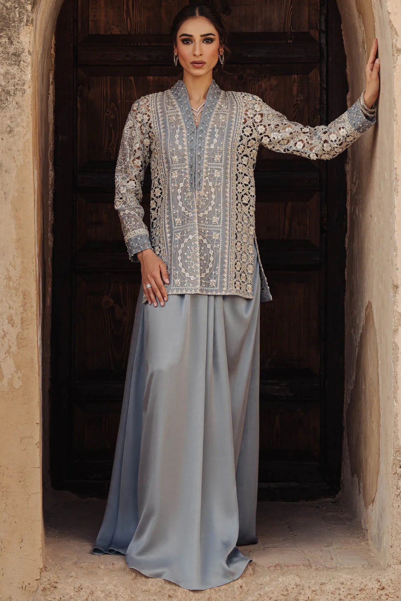 Woman in an embroidered traditional outfit standing in a doorway.