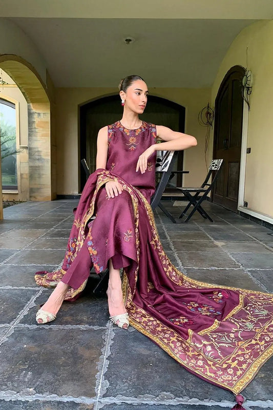 Woman in a purple embroidered dress sitting on a stone floor.