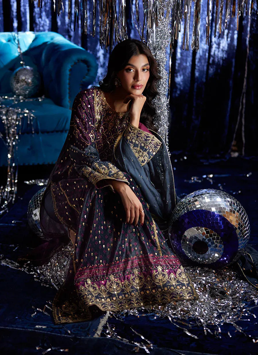 Woman in an ornate traditional outfit sitting among festive decorations with disco balls and tinsel.