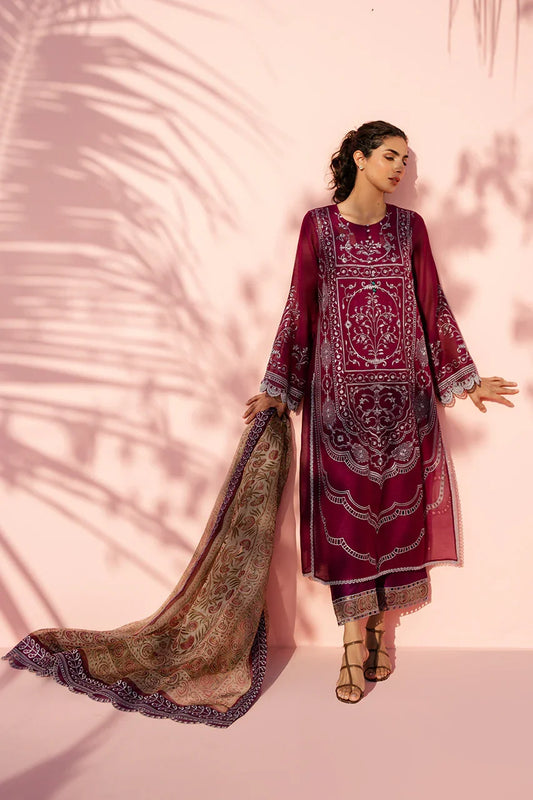 Woman wearing a maroon embroidered traditional outfit with a pink background