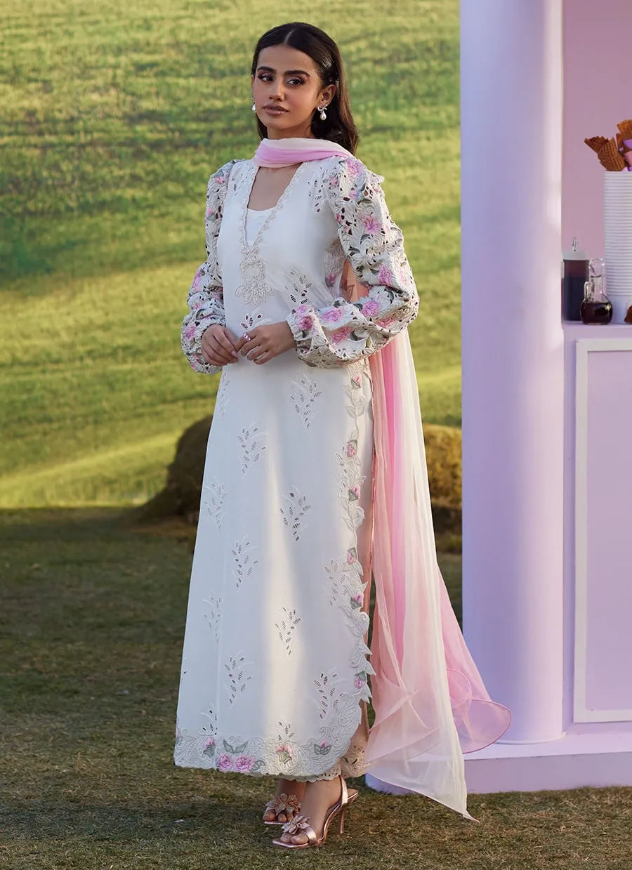Woman in a white and pink traditional outfit standing outdoors.