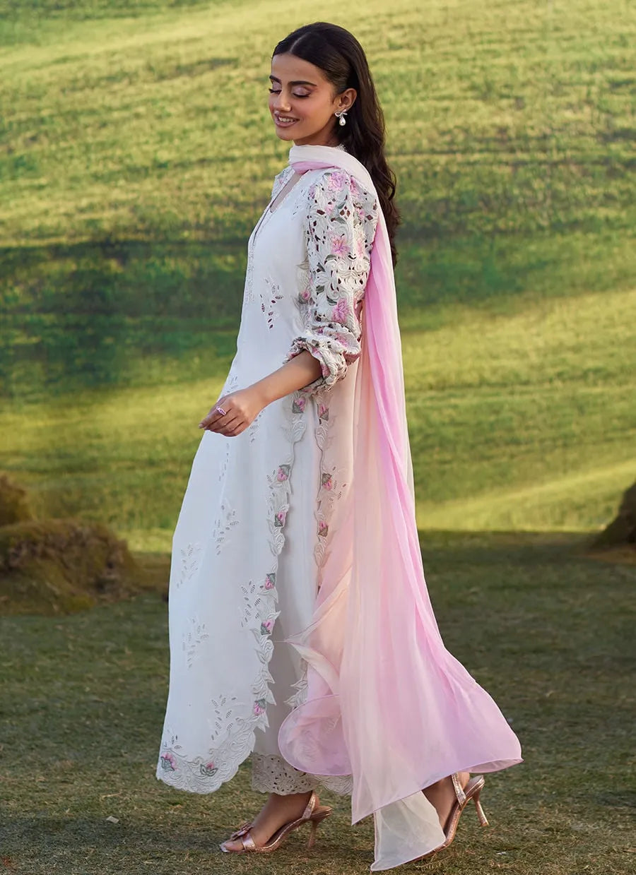 Woman in a white and pink traditional outfit standing in a field.