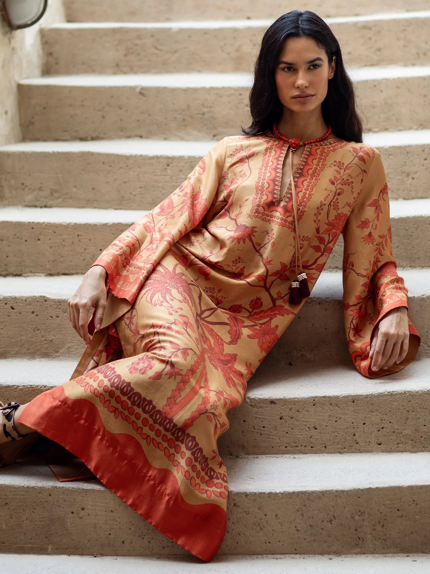 Woman in a patterned dress sitting on stone steps