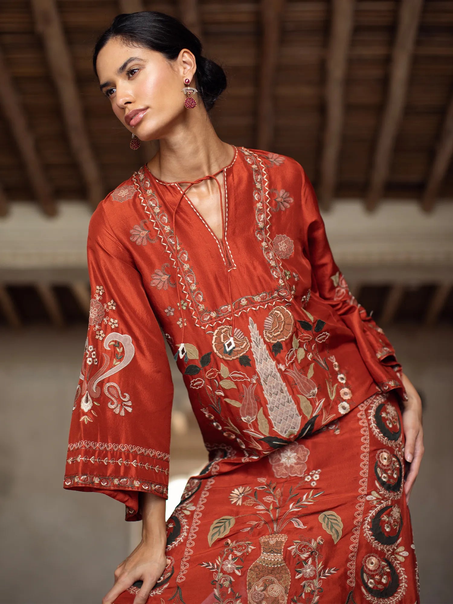 Woman wearing a red embroidered outfit in a warm-toned setting