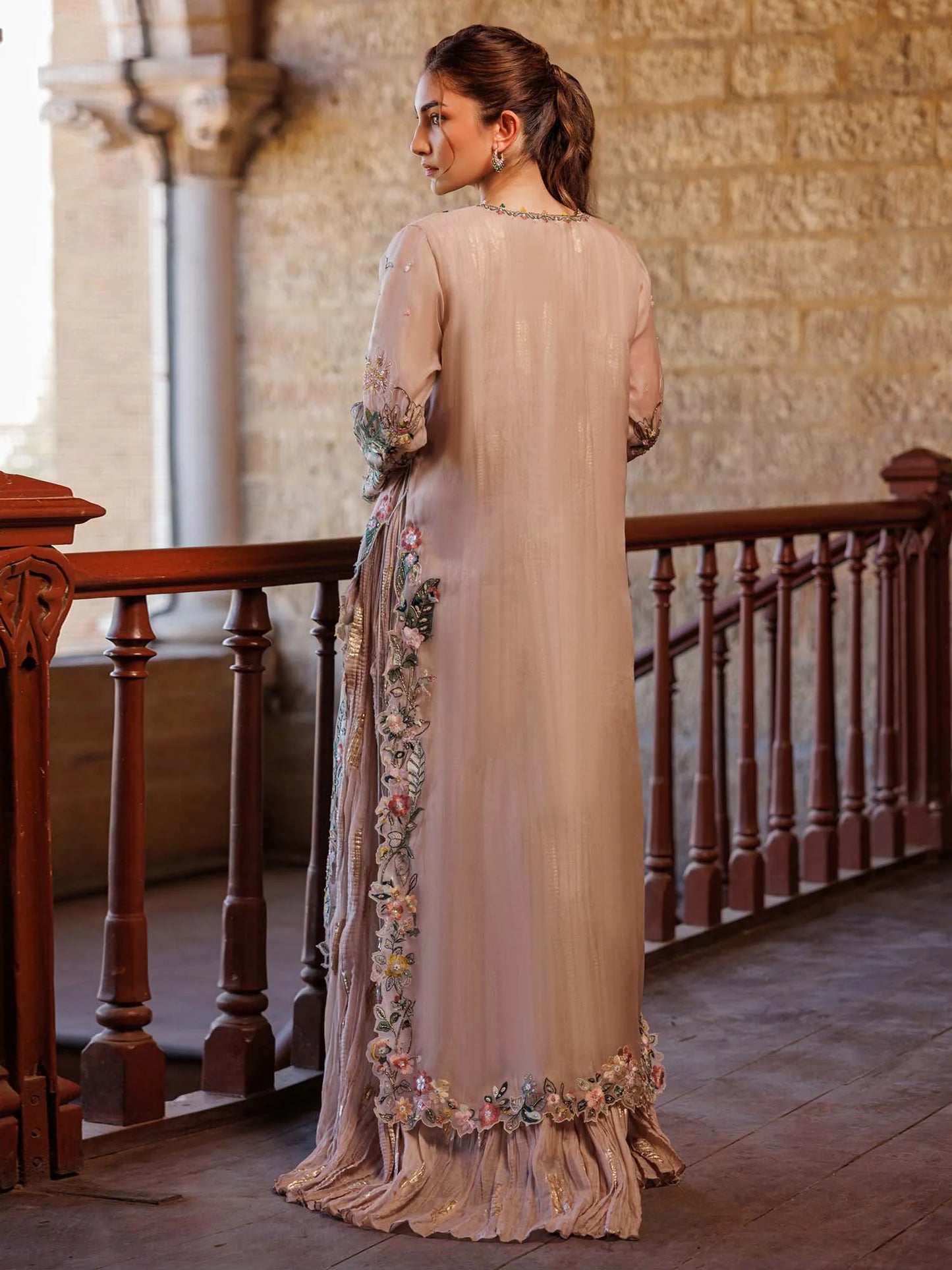 Woman in a beige floral dress standing in an elegant interior setting