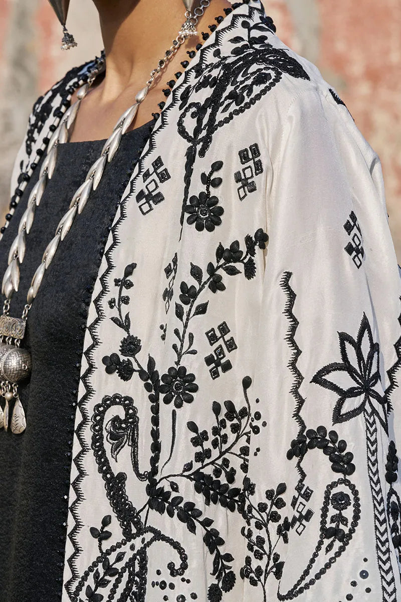 Person wearing a black and white embroidered shawl with a blurred background