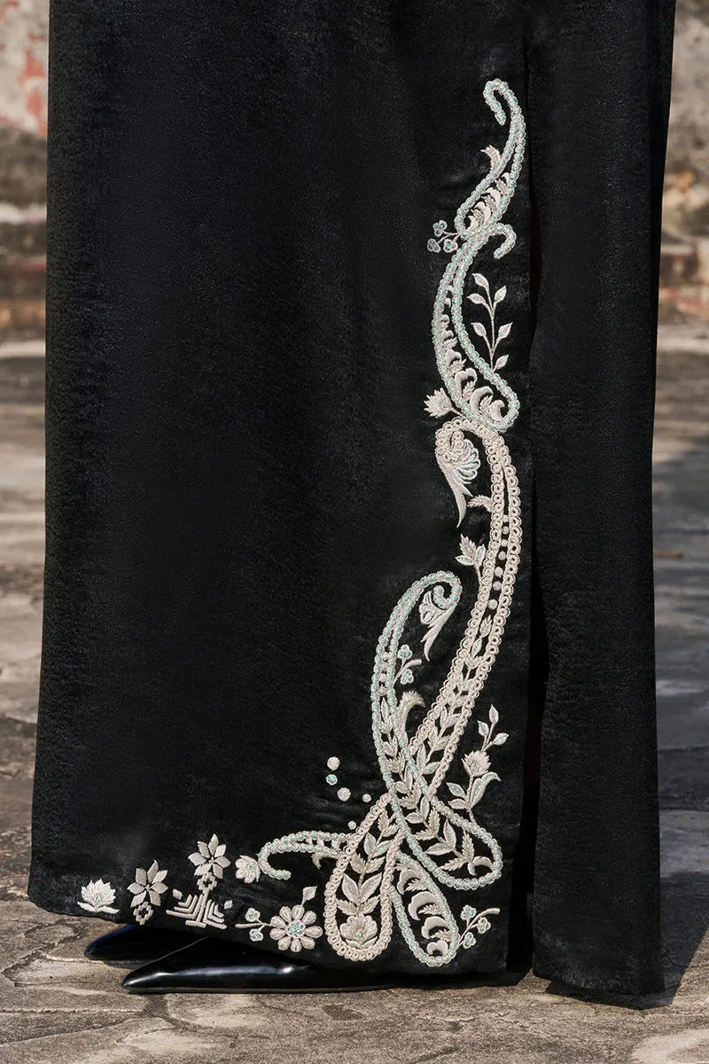 Black fabric with intricate white embroidery on a textured surface
