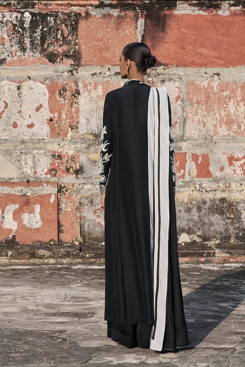 Person wearing a black and white dress with a textured wall background