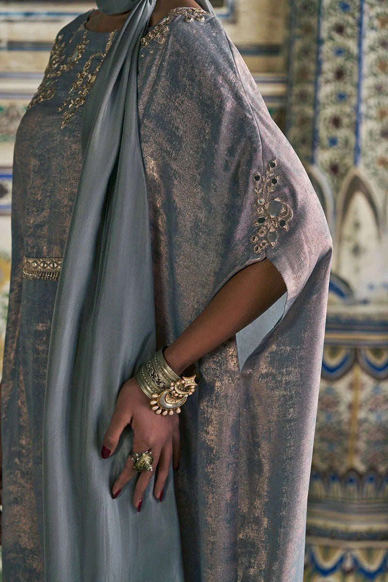 Person wearing a patterned garment with gold embellishments in an ornate interior setting.
