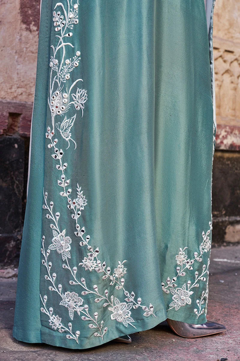 Teal dress with white floral embroidery on a textured surface