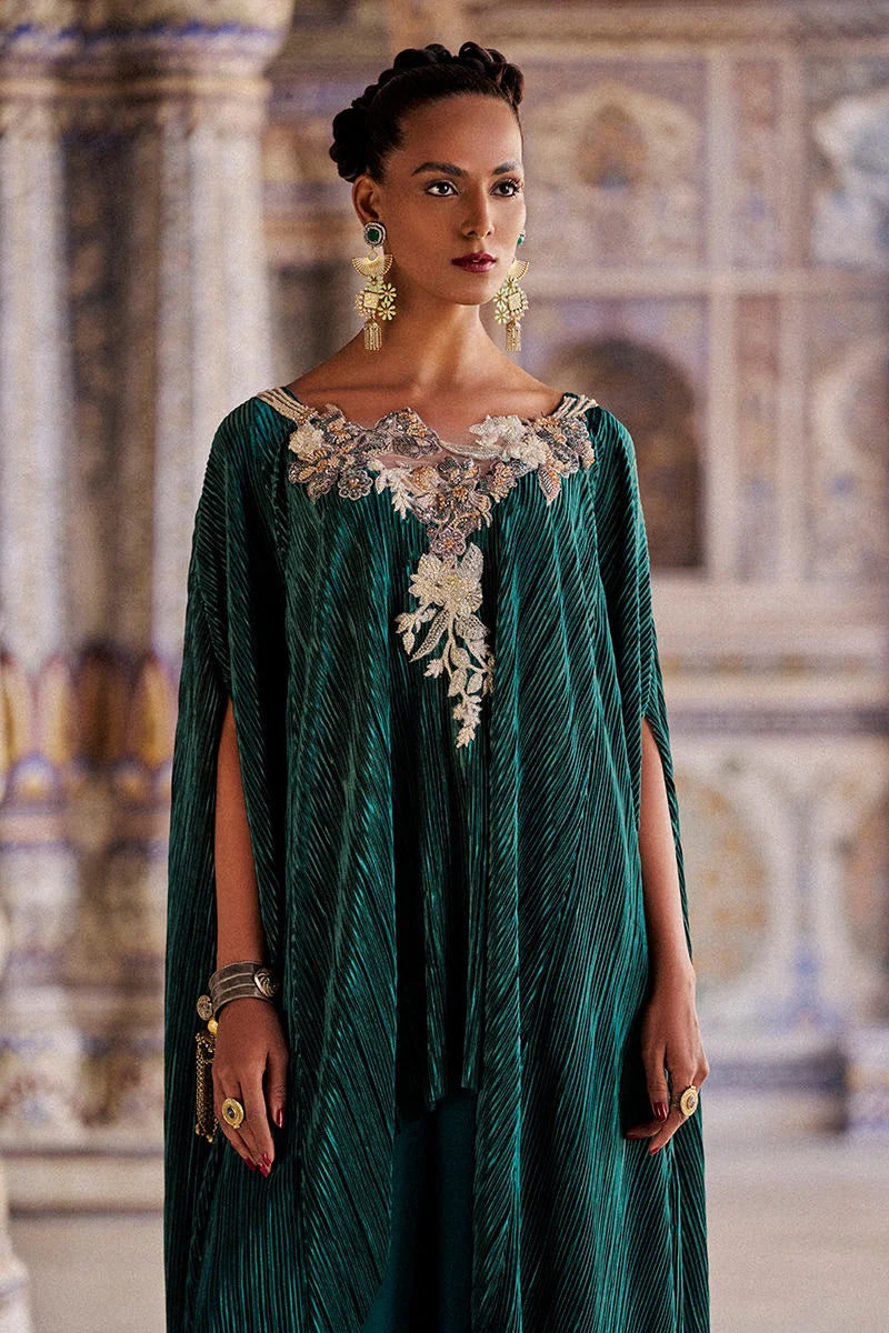 Woman wearing a green dress with floral embellishments in an ornate interior setting