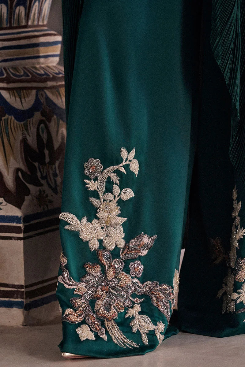 Teal fabric with intricate silver floral embroidery on a patterned rug background