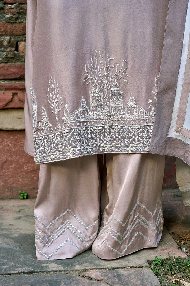 Beige traditional outfit with intricate white embroidery against a stone wall background