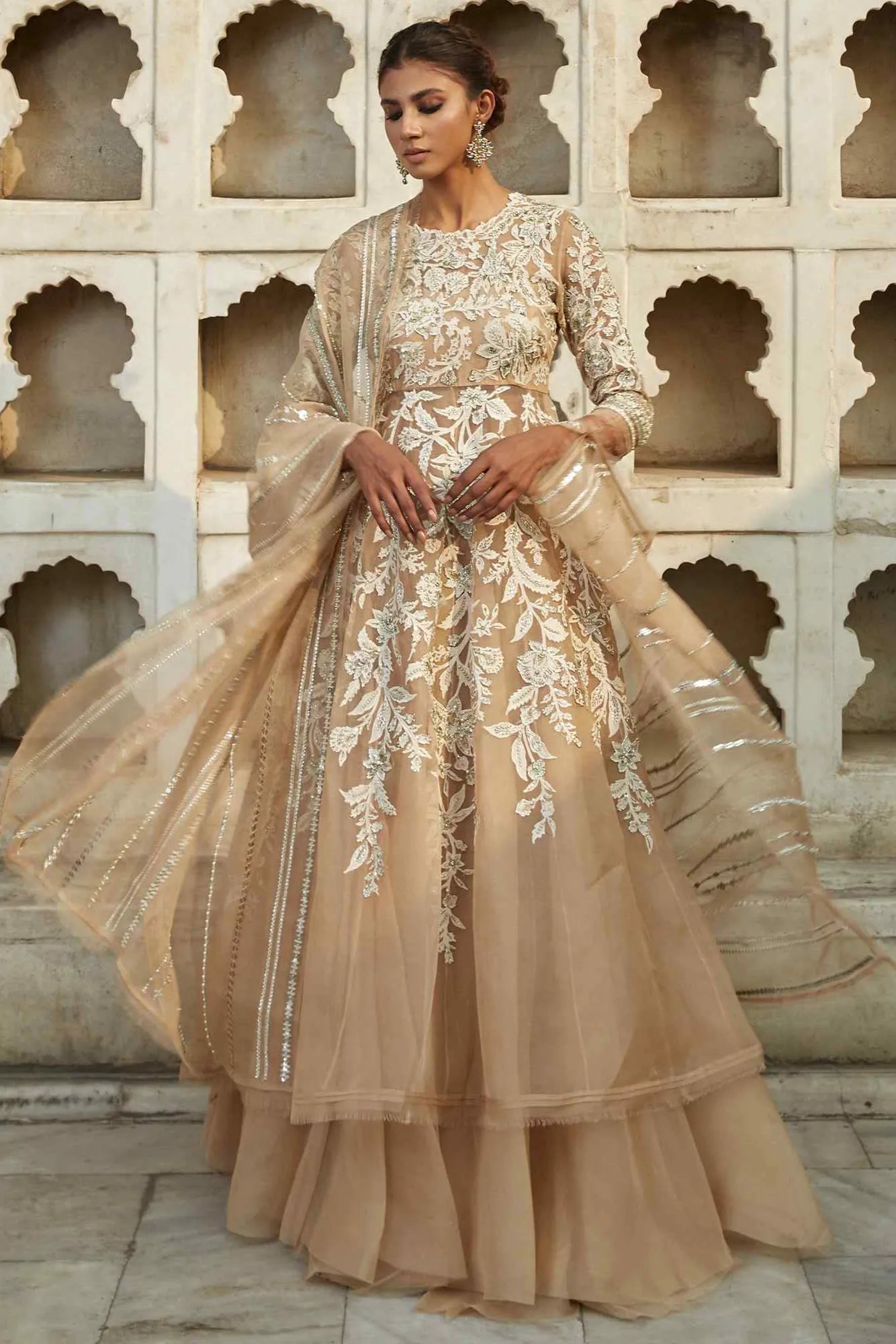 Woman wearing a beige embroidered dress with a light background