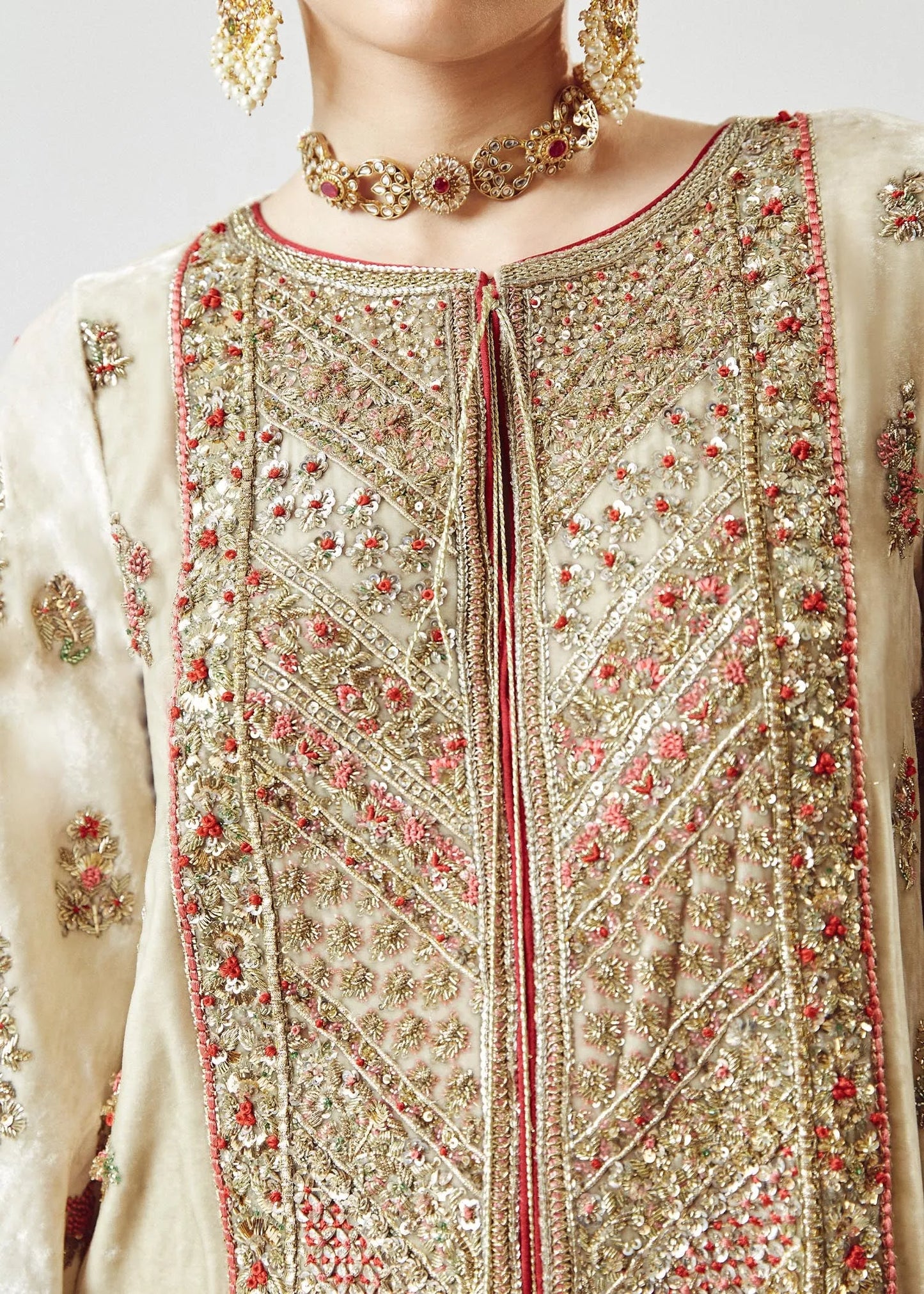 Close-up of a person wearing an intricately embroidered traditional outfit with gold and red details.