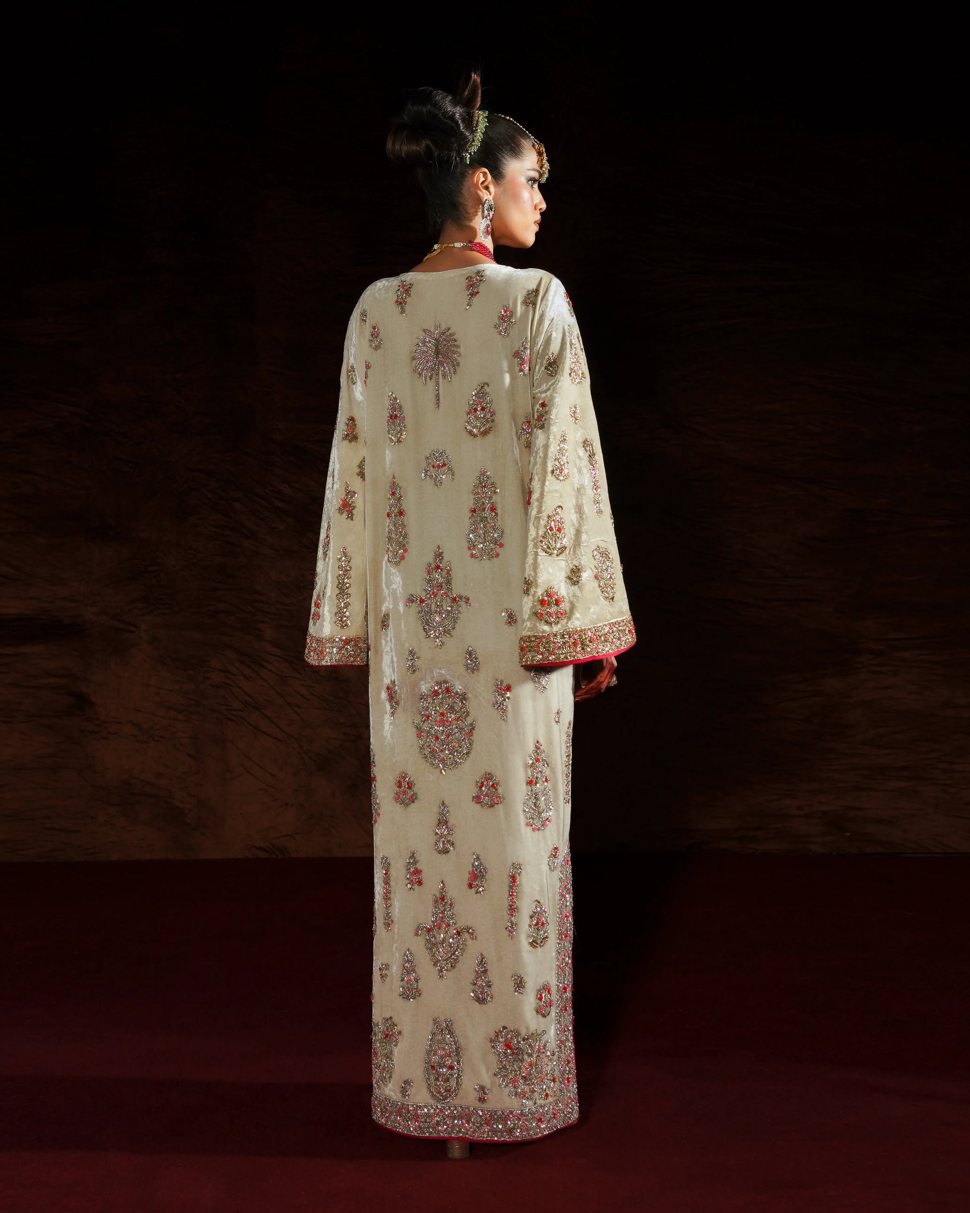 Woman wearing a white embroidered outfit with red details on a dark background