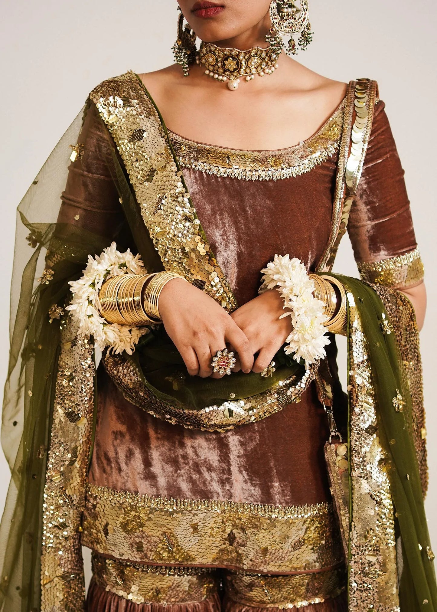 Traditional outfit with gold and brown details, holding a decorative basket.