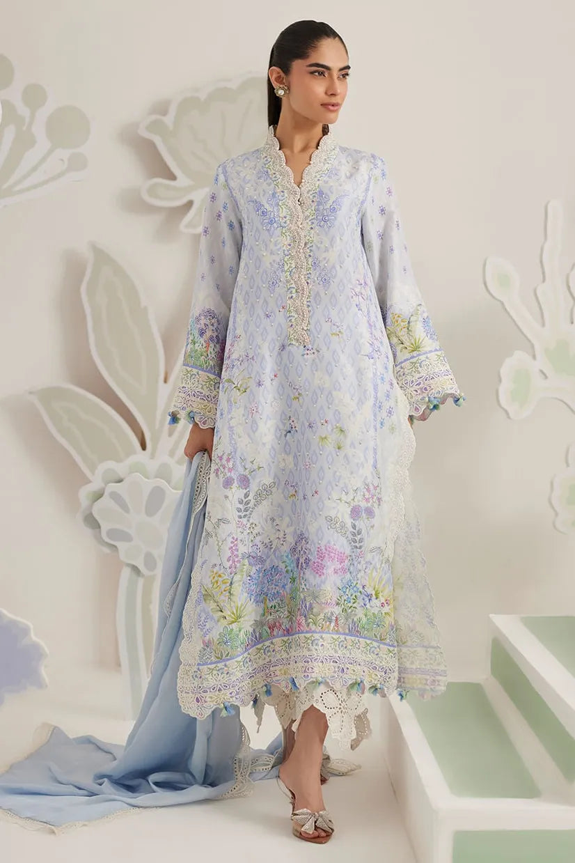 Woman wearing a floral embroidered dress with a light blue dupatta against a white background