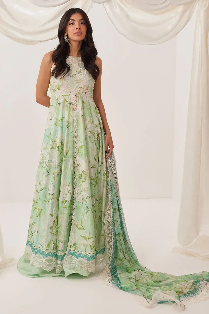 Woman wearing a long, light green floral dress with a matching shawl against a white curtain background.