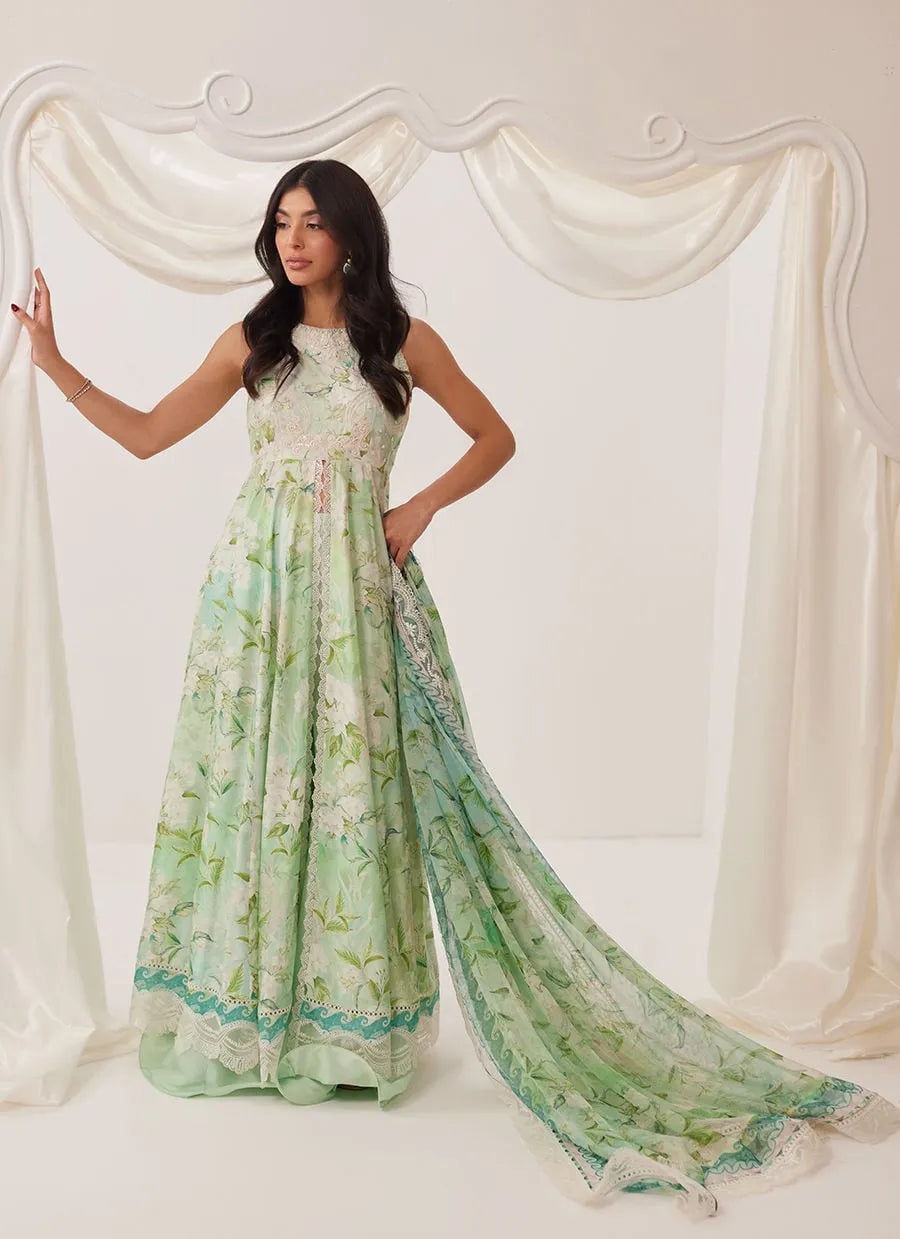 Woman wearing a green floral dress against a white curtain backdrop