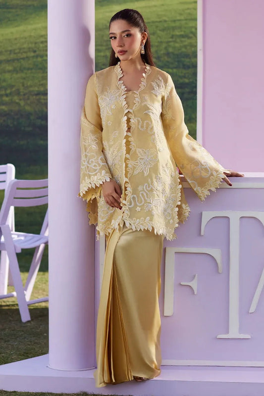 Woman in a yellow lace outfit standing next to a pink 'T' sign.
