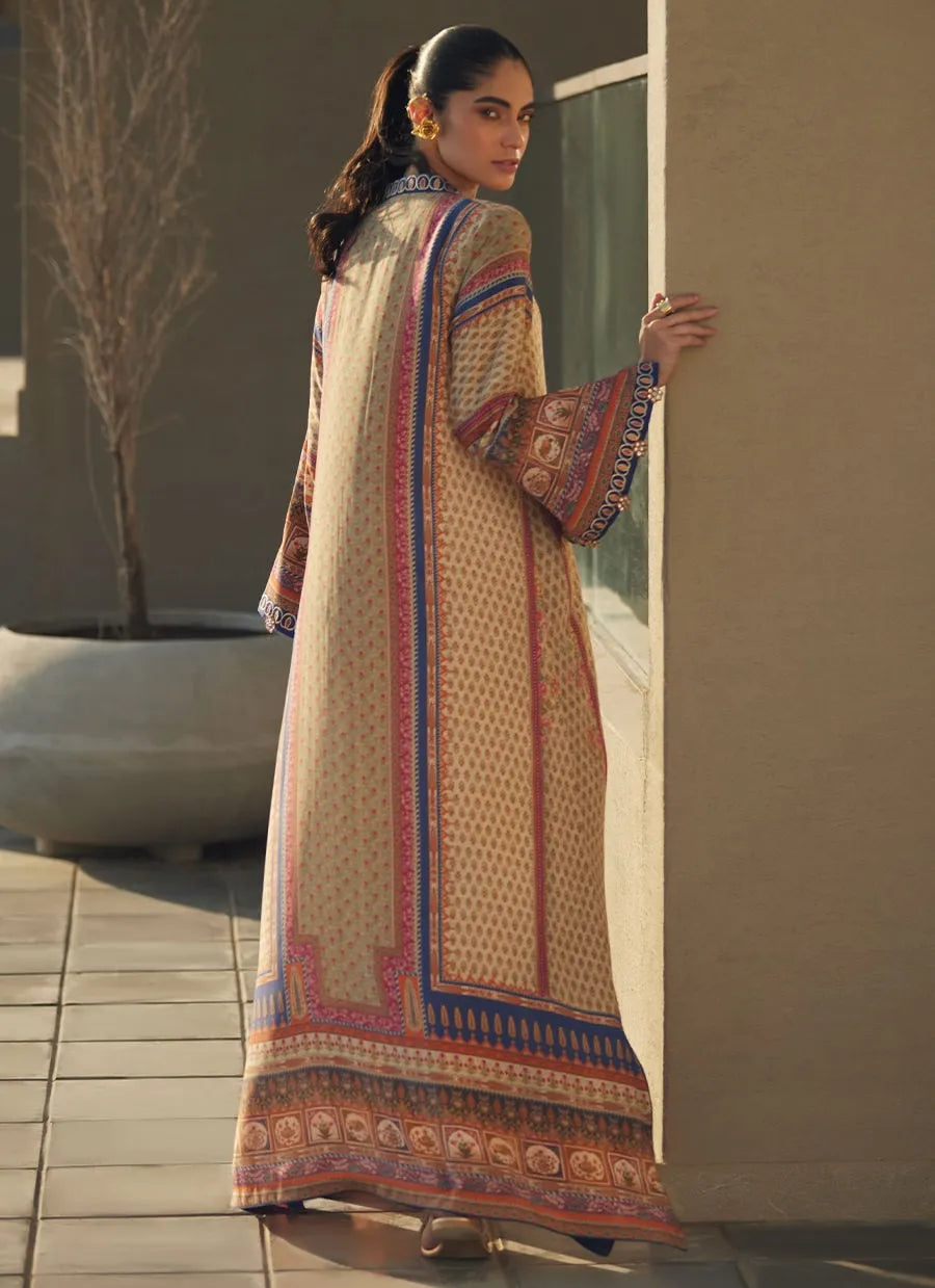 Woman in a patterned dress standing against a neutral wall.