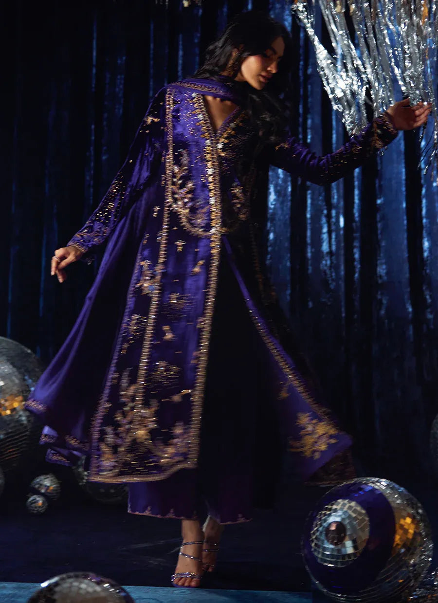 Person wearing a purple embroidered outfit with a dark curtain and decorative elements in the background
