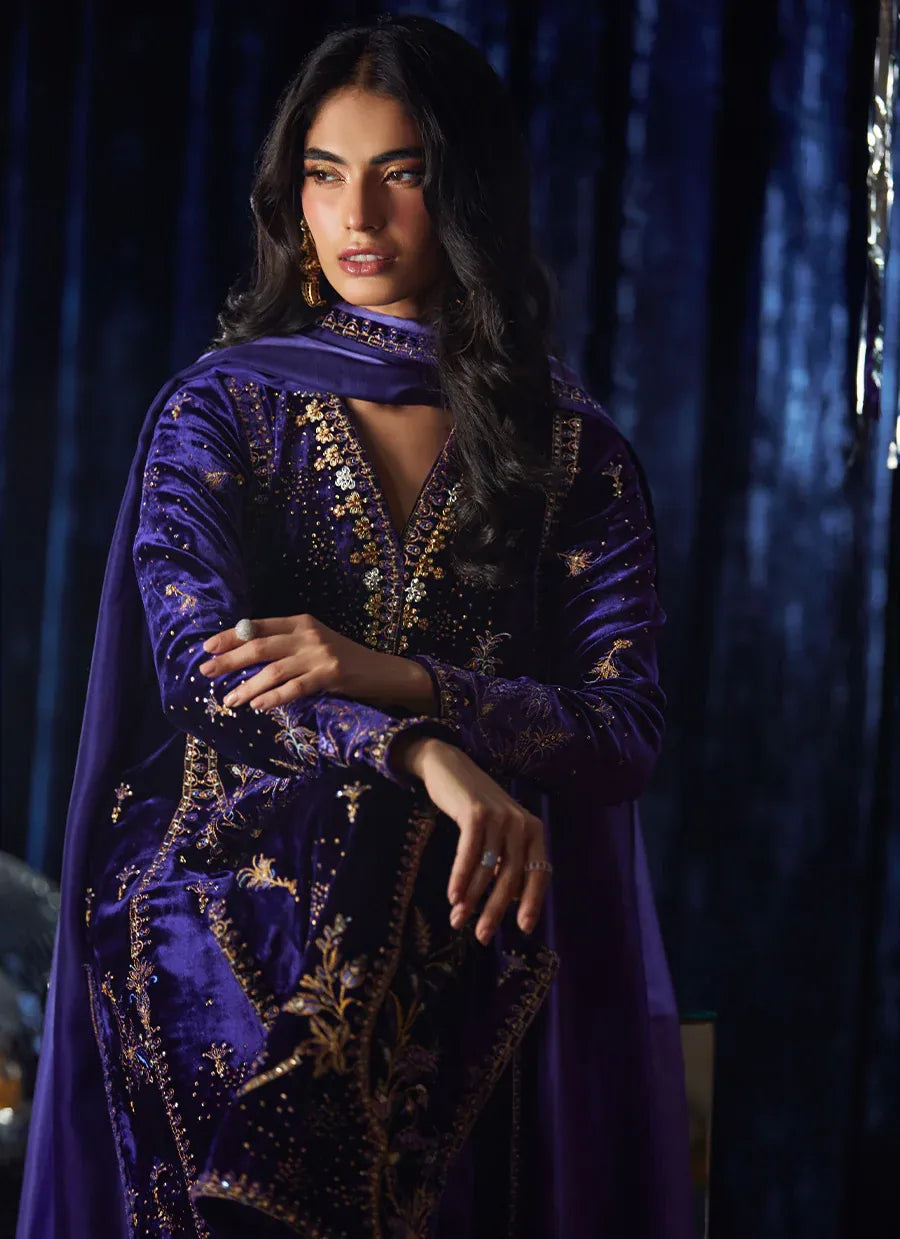 Woman wearing a purple embroidered outfit against a dark background