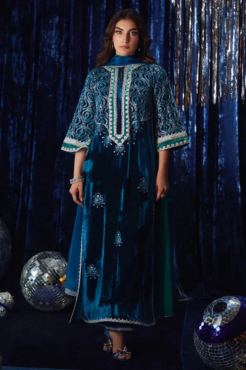 Woman wearing a blue embroidered dress against a dark, reflective background with disco balls.