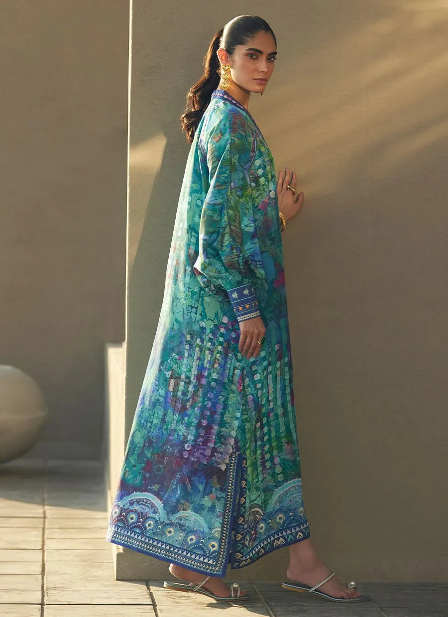Woman wearing a long, colorful dress with a pattern against a beige wall.
