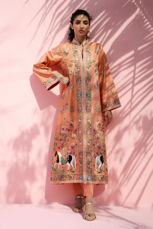 Woman wearing a peach embroidered traditional outfit against a pink background