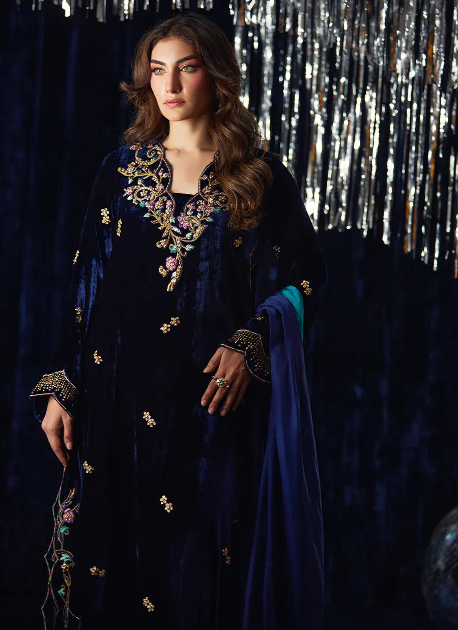 Woman wearing an embroidered dark blue traditional outfit with a silver curtain background