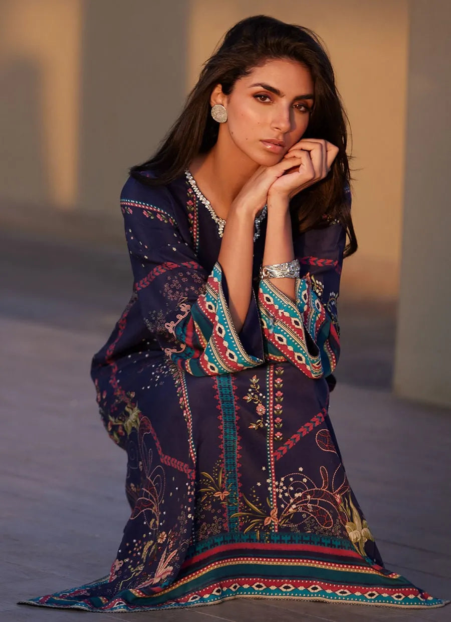 Woman wearing a colorful, patterned dress sitting on a textured surface.