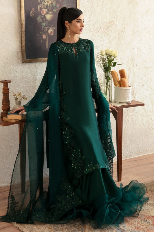 Woman in a green traditional outfit with floral patterns in an indoor setting.